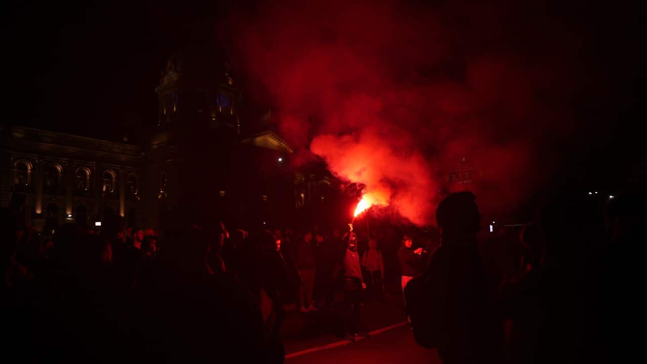 Explosion in background of large group of people in the dark