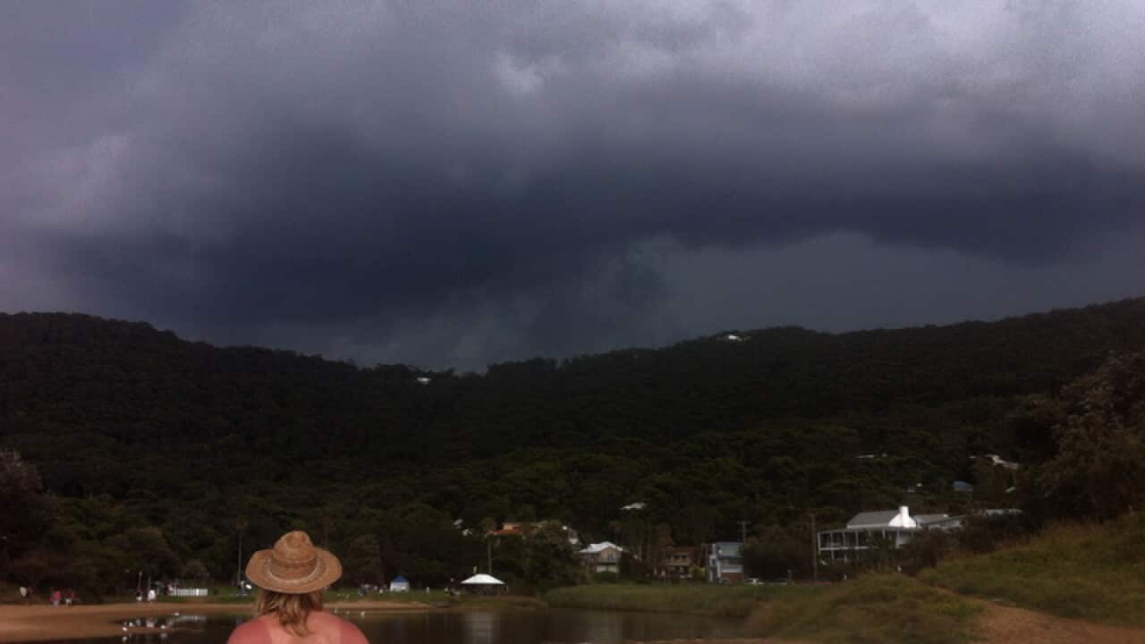 Beach goers watch as a thunderstorm moves in over Stanwell Park