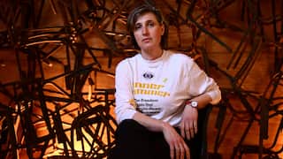 Australian Jewish artist Nina Sanadze poses for a photograph in front of an artwork featuring burnt chairs from the Adass Israel Synagogue.