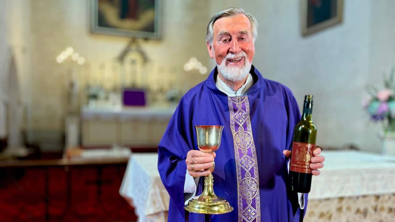 Father Brendan Kelly, Superior at Sevenhill Jesuit Mission in South Australia, holding sacramental wine which is still made on site, as it has been for 175 years. (SBS -Lloyd Thornton).jpg