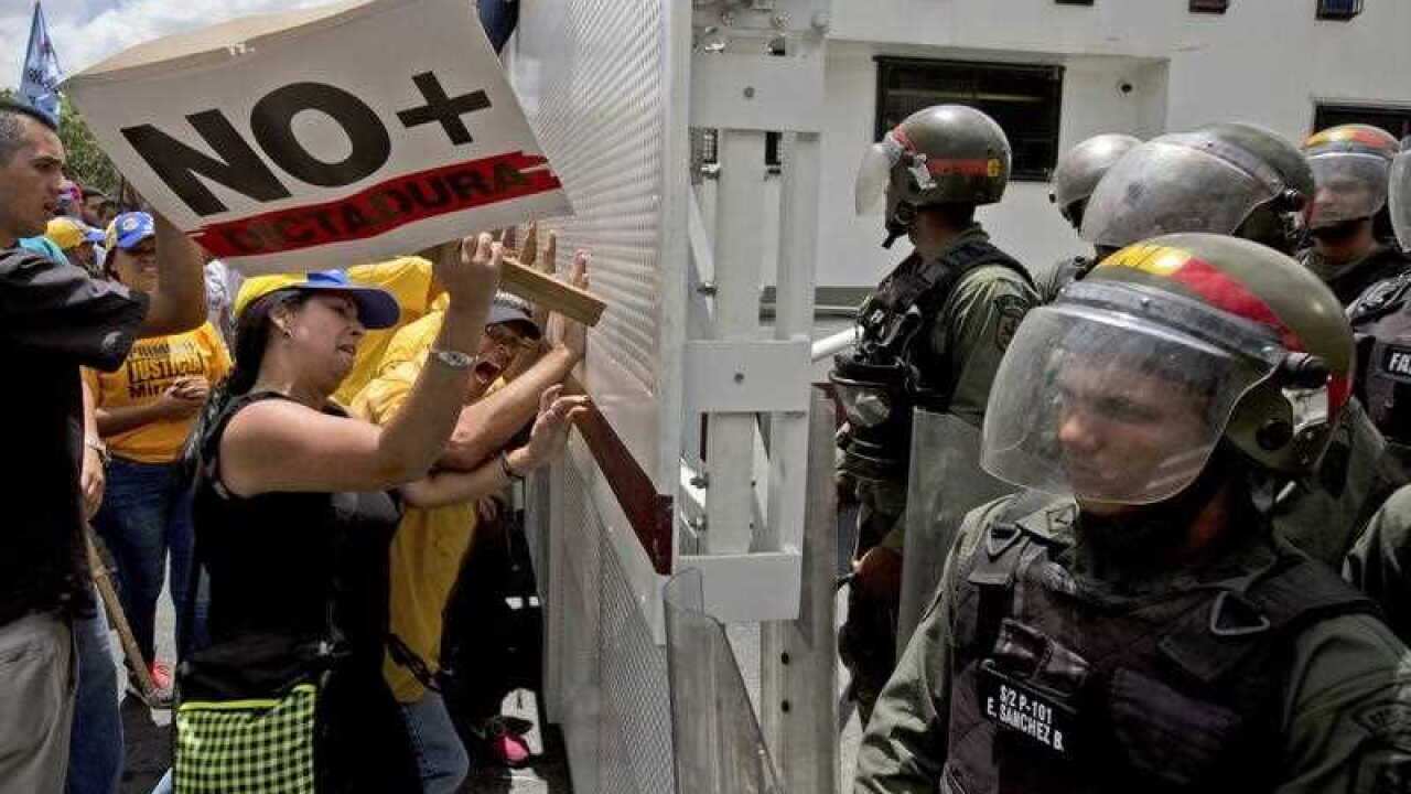 An opposition member hits a barricade with a sing that reads in Spanish: " No more dictatorship," during a protest in Caracas, Venezuela