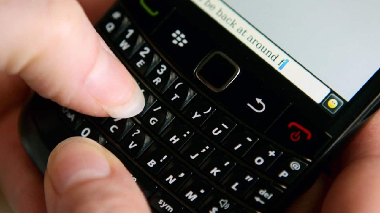 A woman writing a message on a BlackBerry