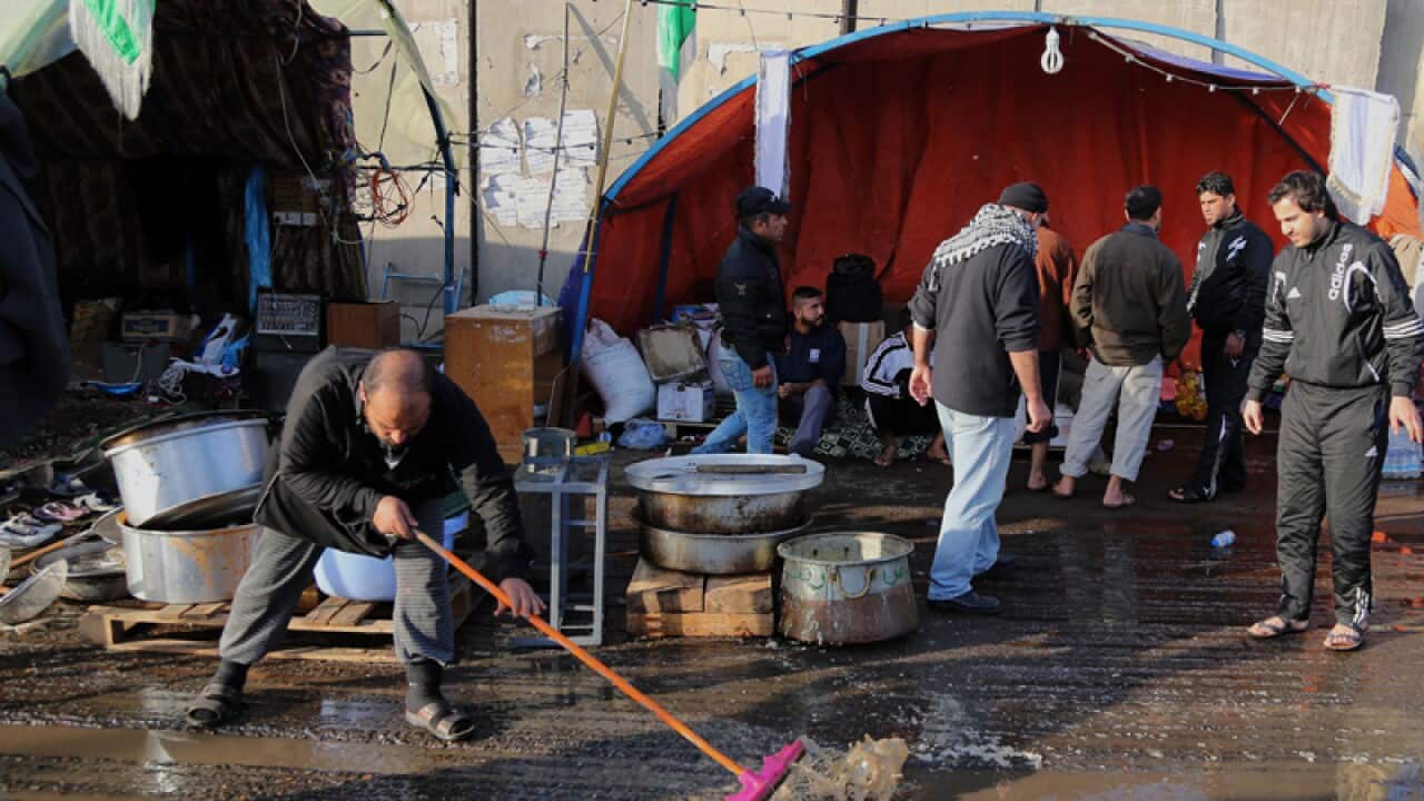 A man cleaning the site of a suicide bombing in Dora