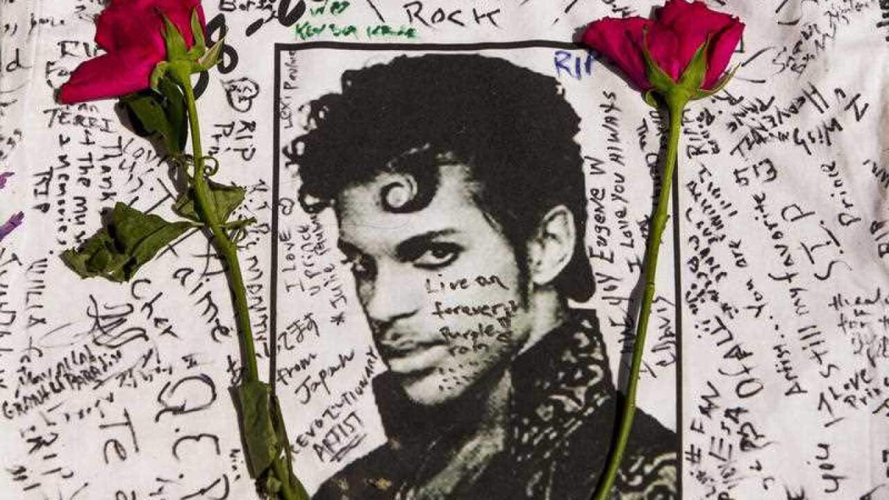 Flowers lay on a T-shirt signed by fans of singer Prince at a makeshift memorial place created outside Apollo Theatre in New York