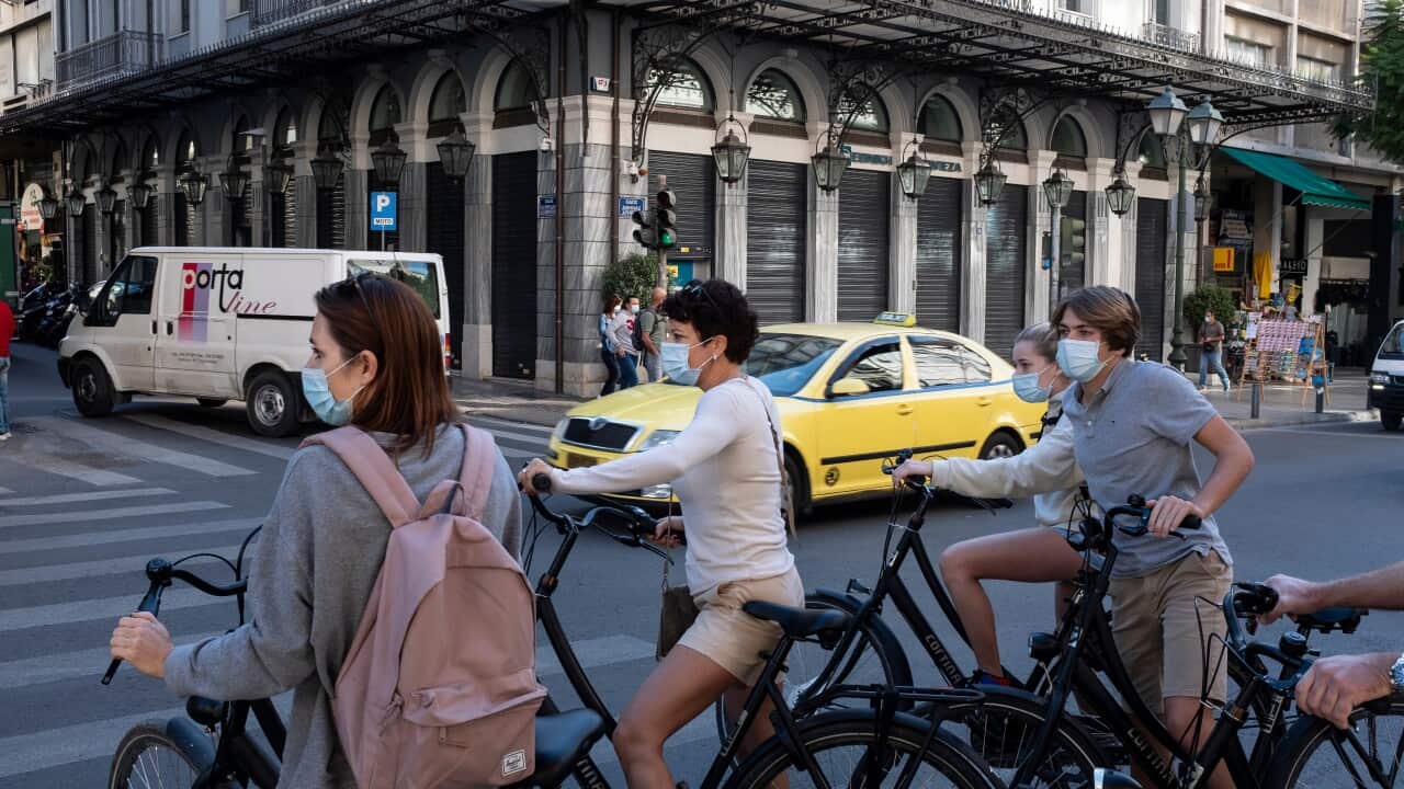 Tourists wearing face masks to prevent the spread of COVID-19 ride bicycles in central Athens, Saturday, Oct. 31, 2020.