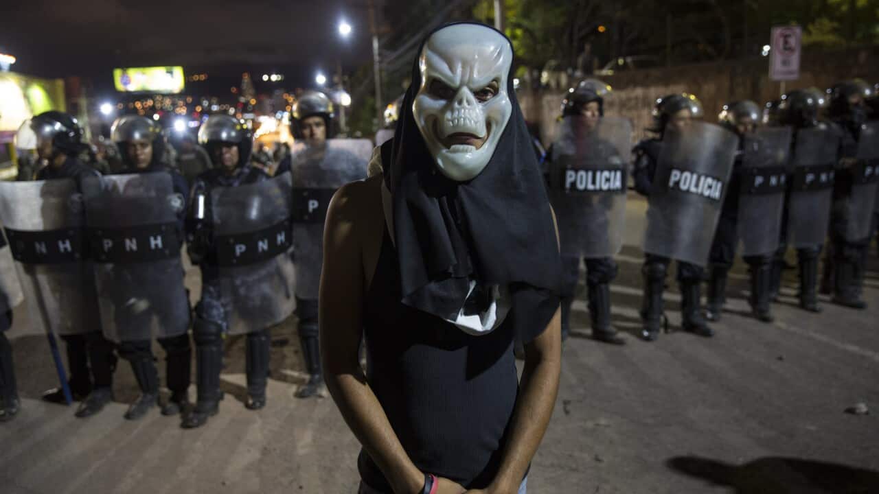 A supporter of presidential candidate Salvador Nasralla stands in front of police during a protest in Tegucigalpa, Honduras.