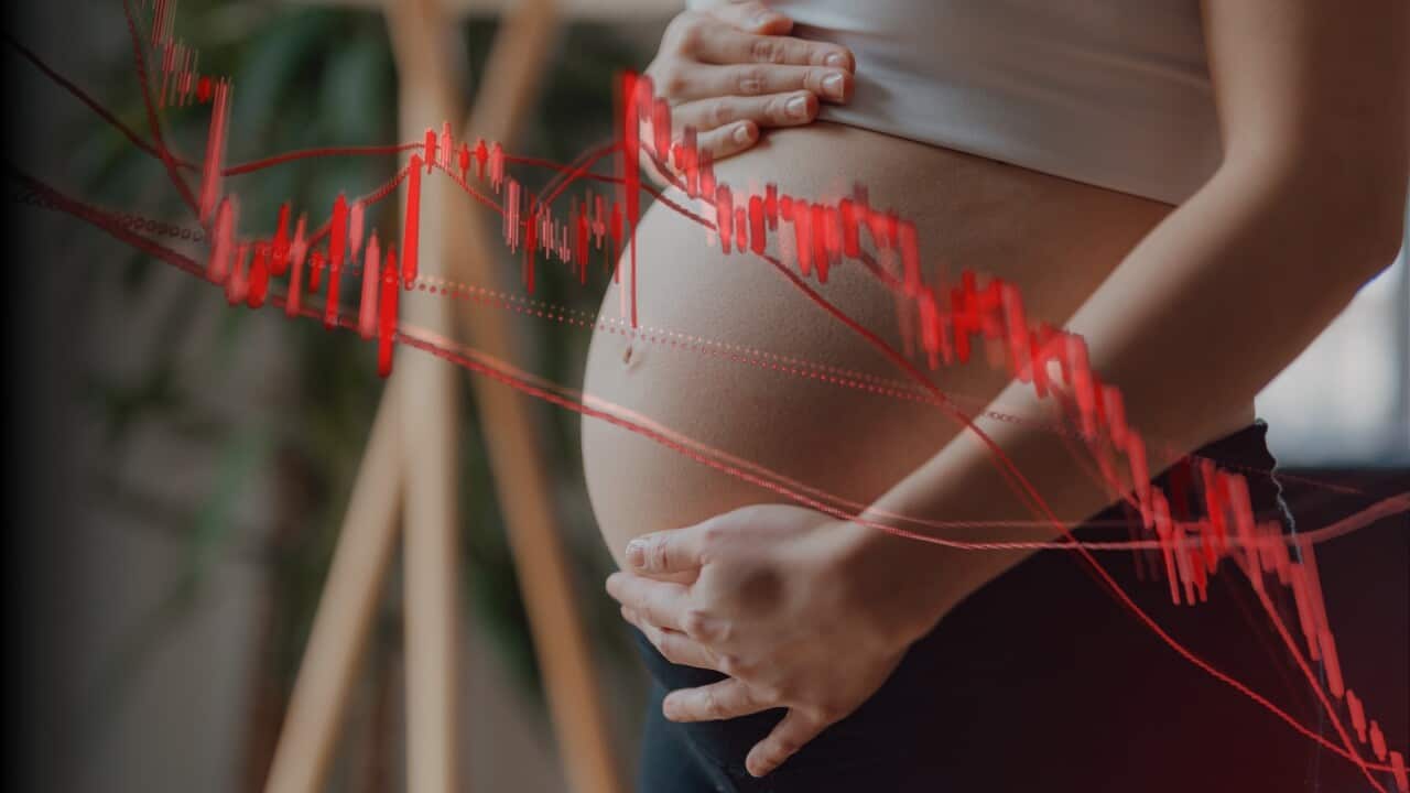An image of a pregnant woman clasping her hands over her belly. In the foreground is a red graph that shows a downward trend.