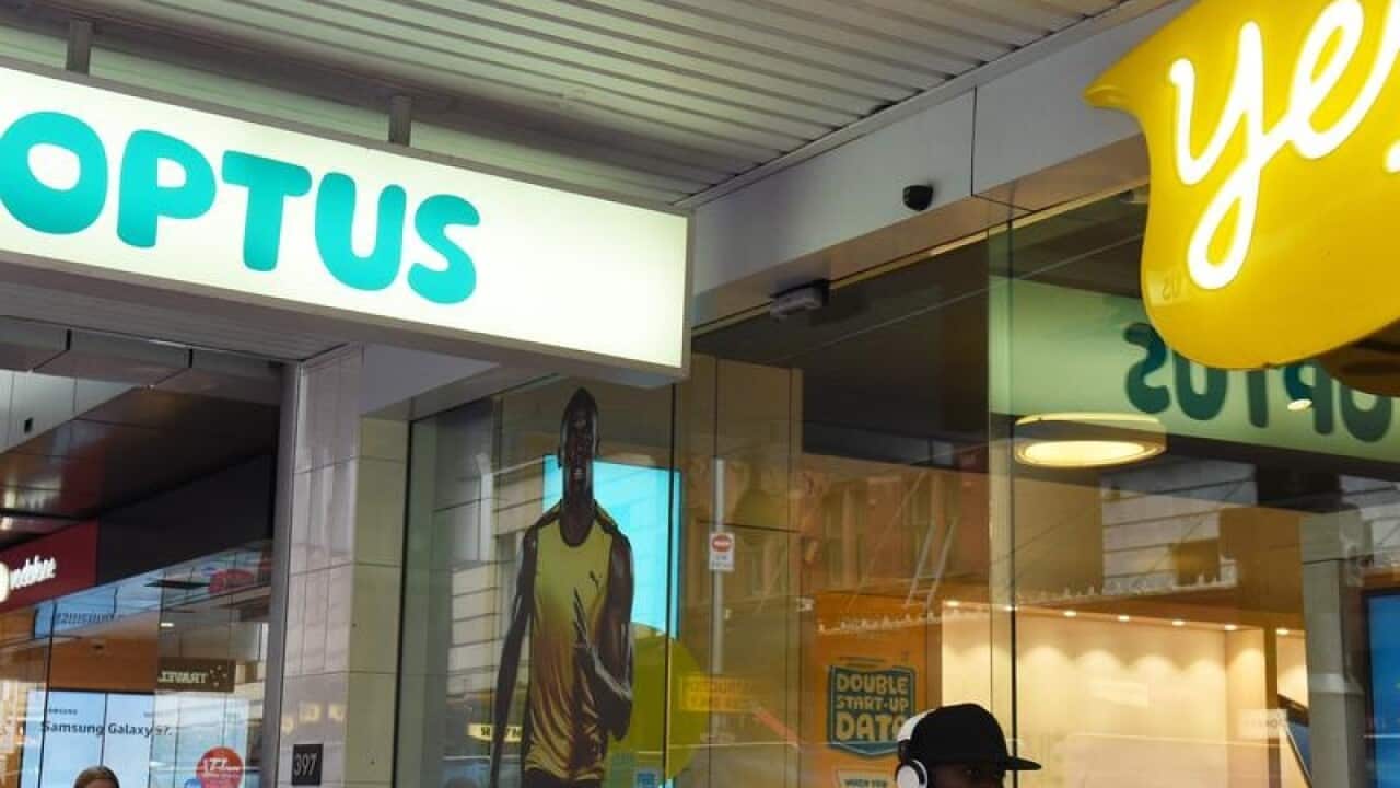 A man walks past an Optus store.