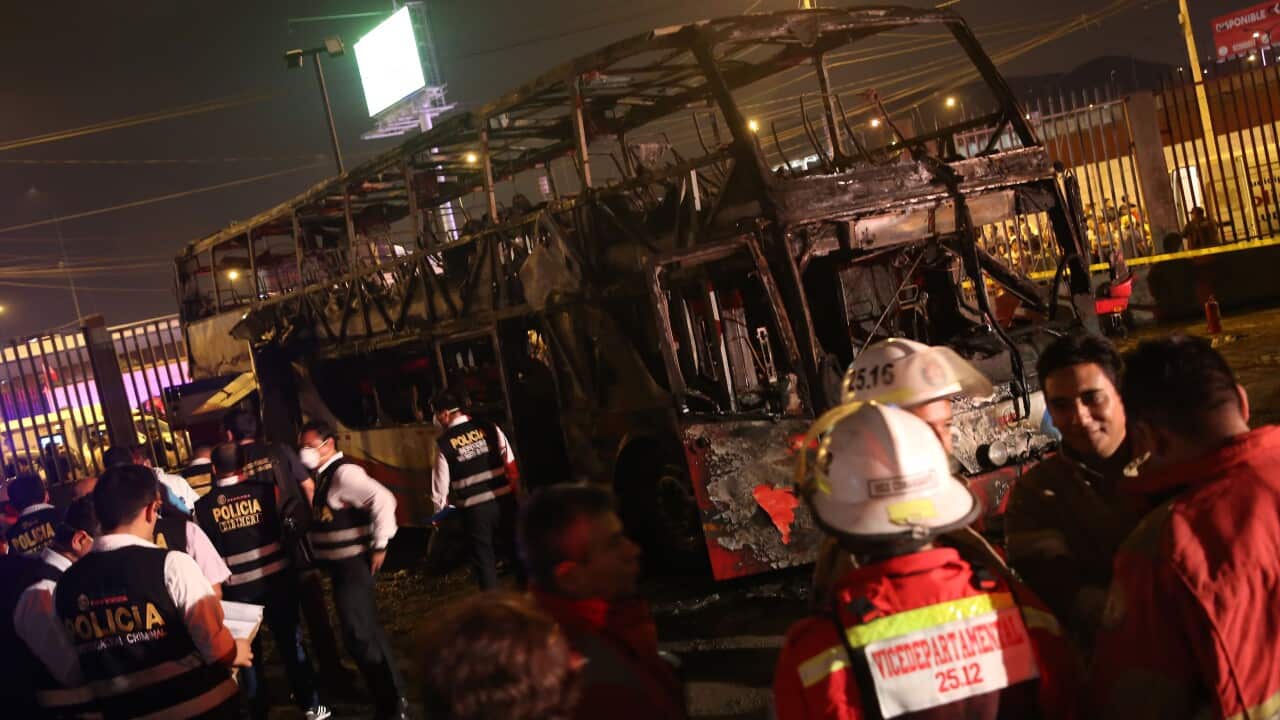 Firefighters and members of the National Police inspect the charred remains of the bus that caught fire in Peru.
