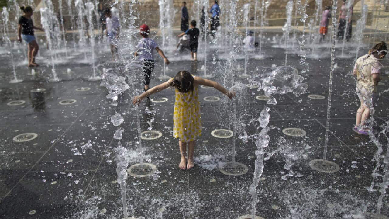 Young Israelis play in a water fountain on a hot day in Jerusalem