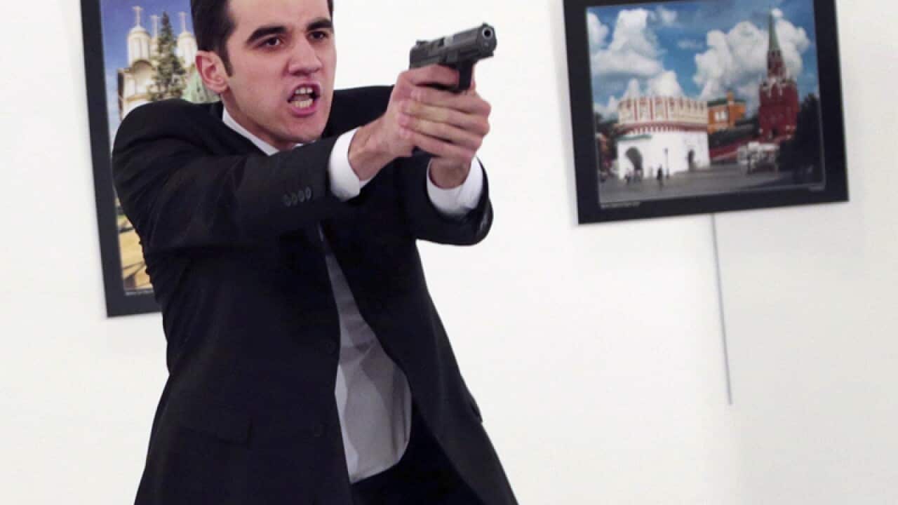 Mevlut Mert Altintas holds up a gun after shooting Andrei Karlov