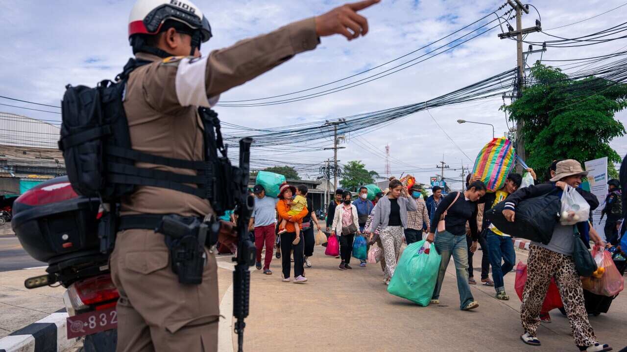 A soldier directing civilians carrying belongings on the Thai-Cambodia border