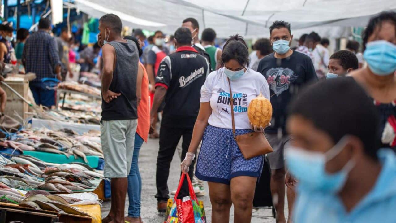 People wear face masks while walking through the fish market in the Fijian capital Suva
