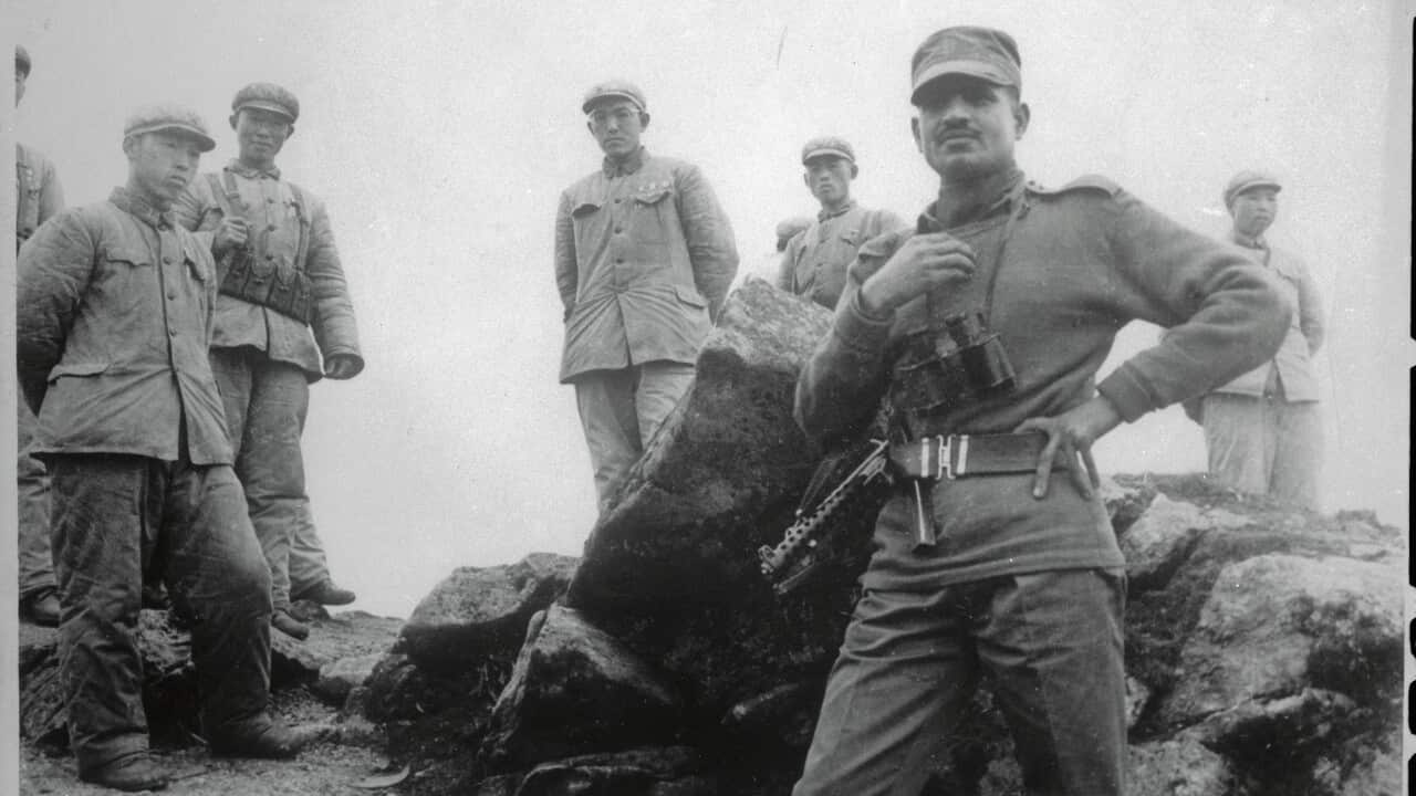 An Indian soldier (right foreground) at Sikkim, Tibet border.The large rock separating the soldiers apparently marks the border.