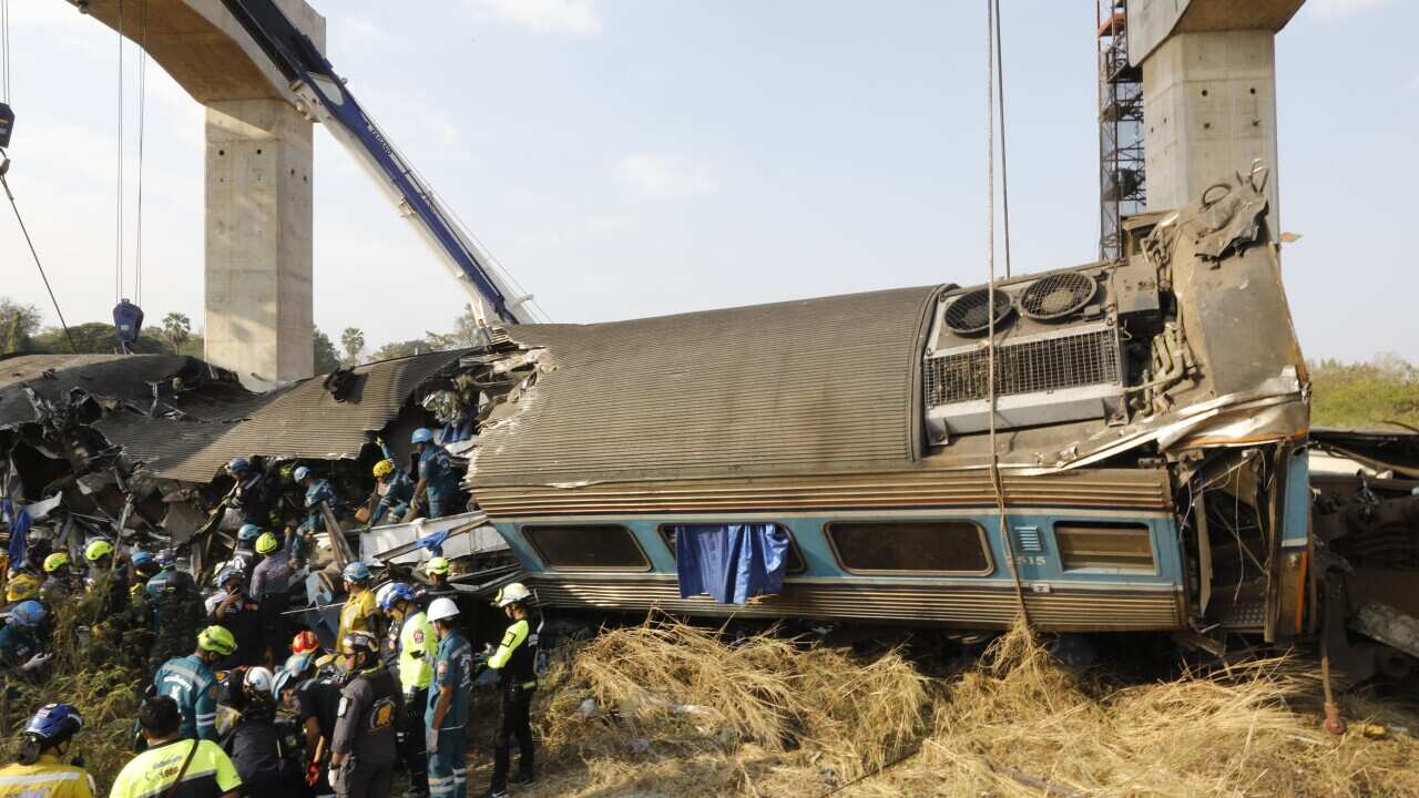Workers are carrying out a rescue operation at the site of a derailed train compartment.