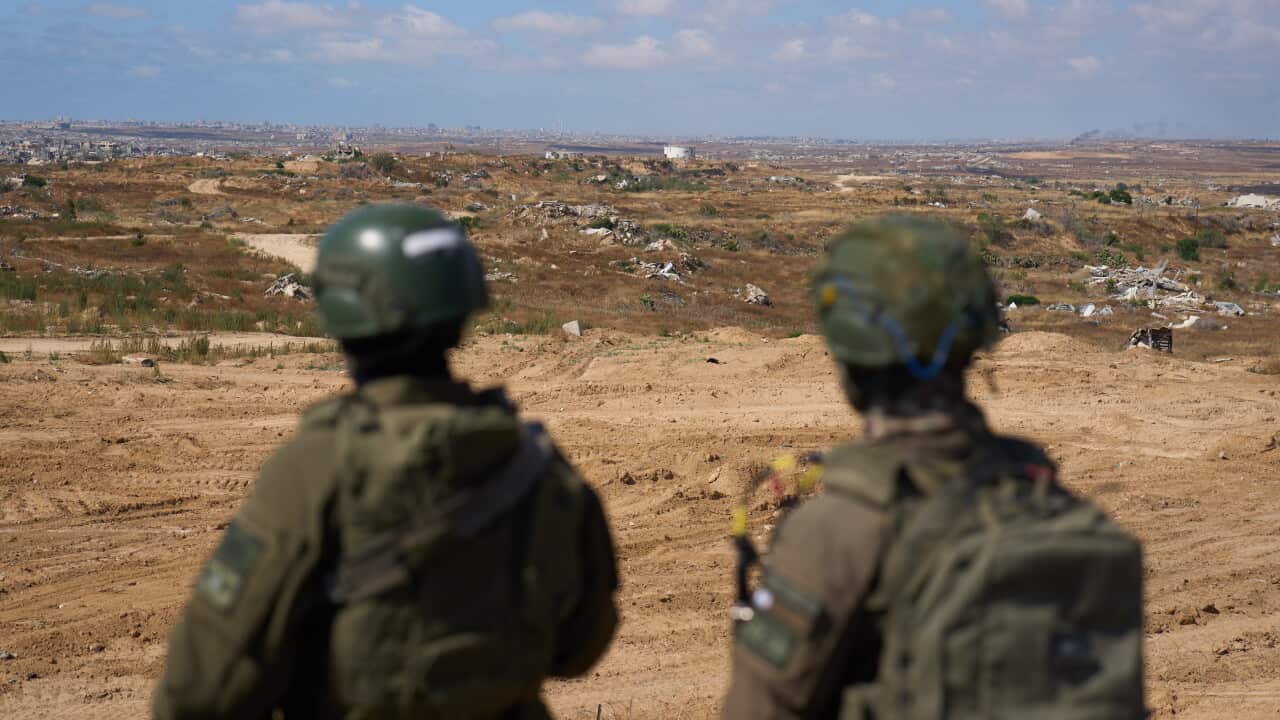 Two soldiers in military uniform staring out at a landscape.