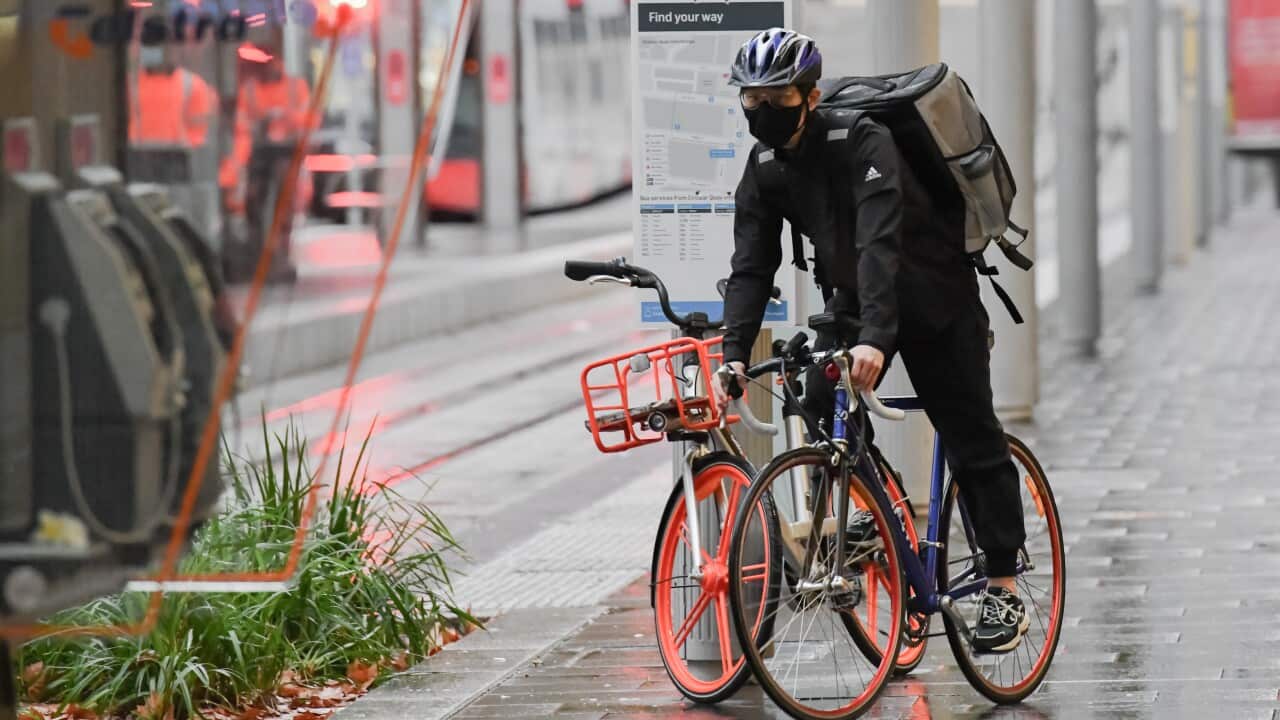 Delivery rider on his bike on the footpath.