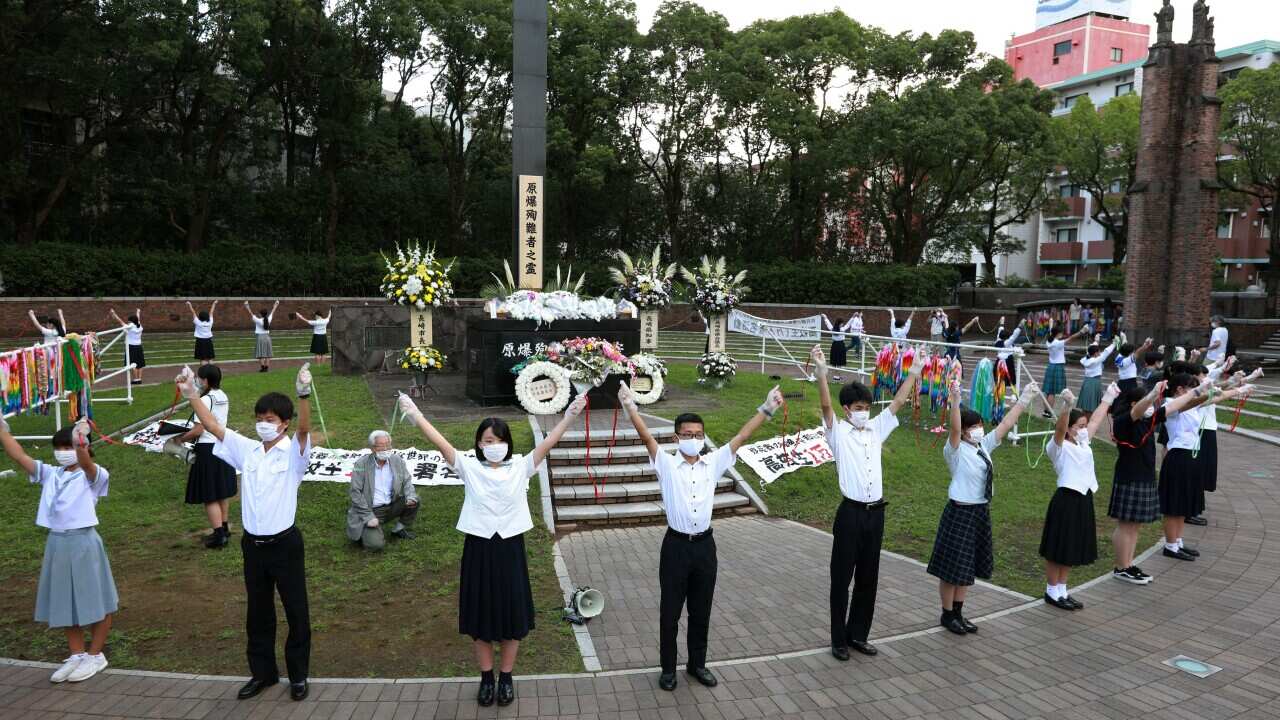 High school students form a human chain around the Hypocenter Cenotaph at Nagasaki Peace Park in Nagasaki, Japan.