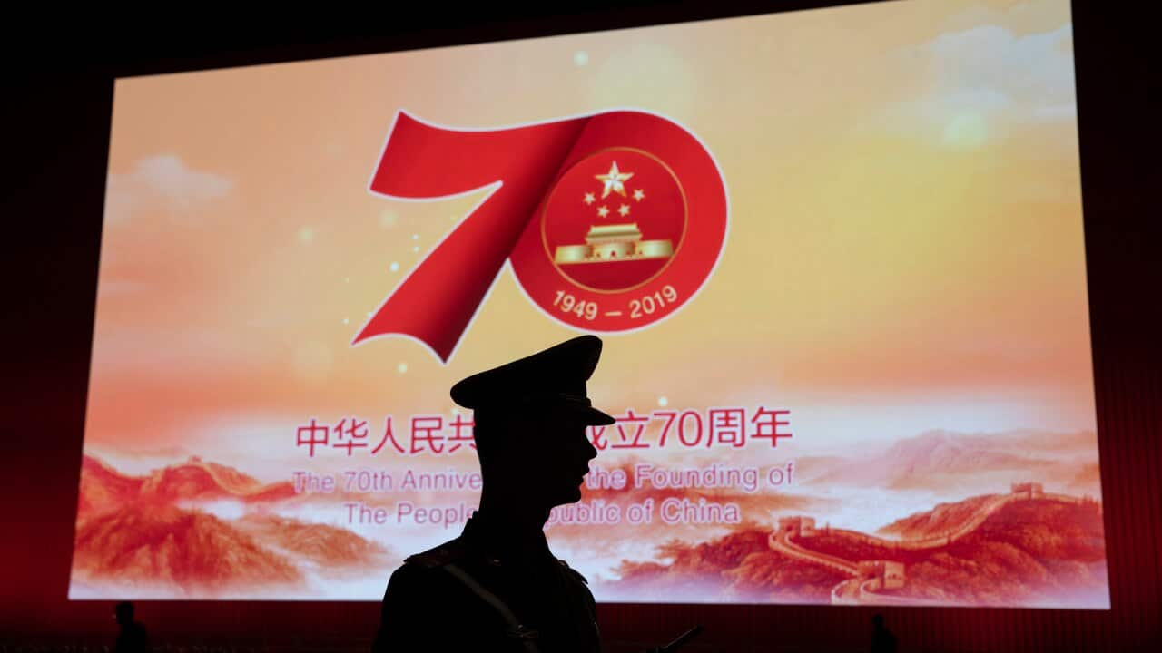 A Chinese paramilitary policeman is silhouetted by a display showing the upcoming 70th anniversary of the Founding of the People's Republic of China in Beijing