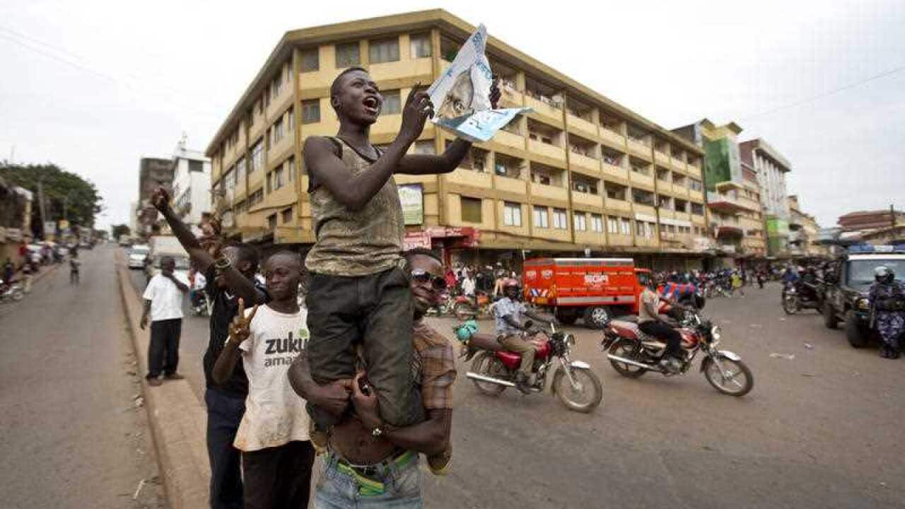 An opposition supporter holds up a poster of opposition candidate Kizza Besigye, who remains under house arrest, shortly after the election result was announced, in downtown Kampala, Uganda