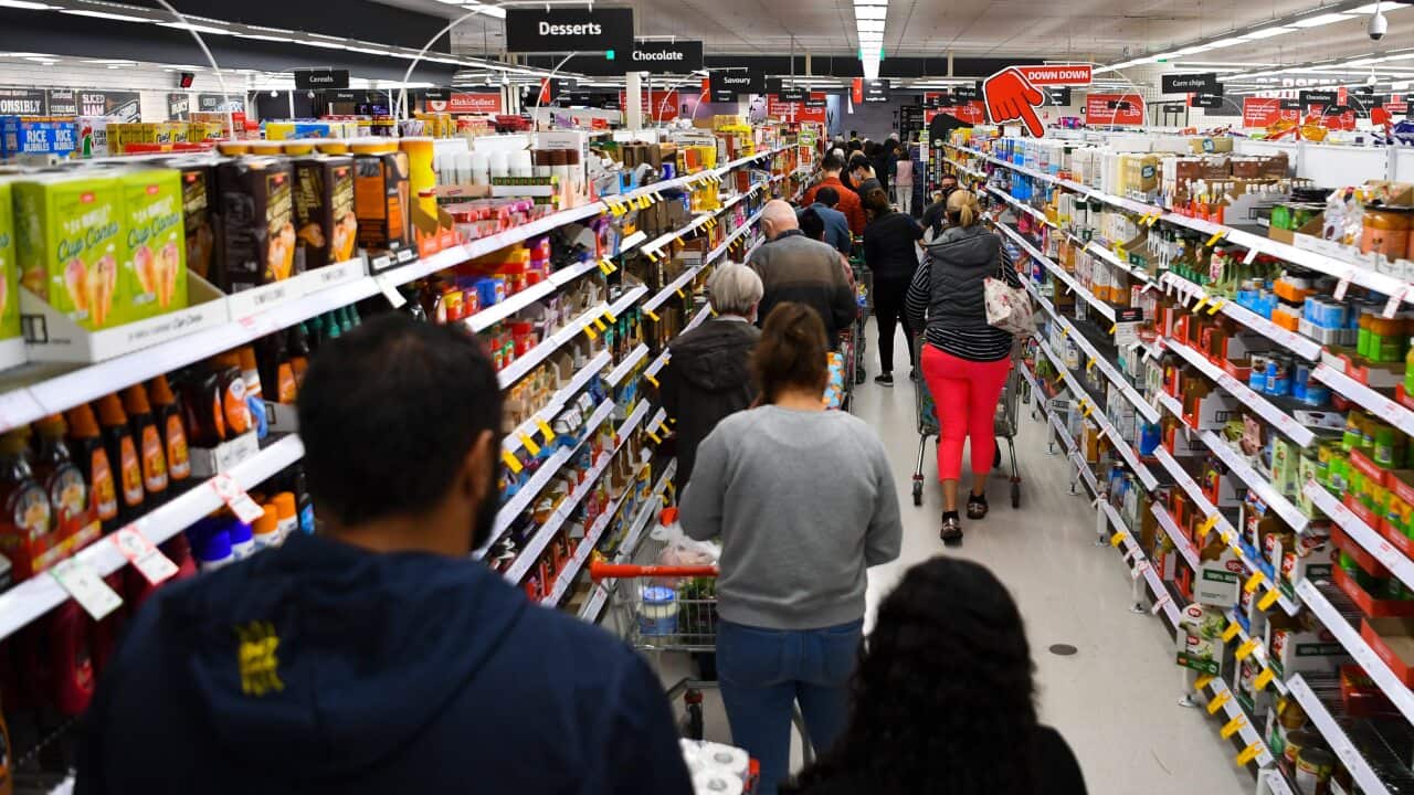 Customers stand in long lines at a check out counter at a Coles supermarket in the Woden area in Canberra, Thursday, August 12, 2021. The ACT is going into a 7 day lockdown after the discovery of the first local COVID-19 case in over a year. (AAP Image/Lu