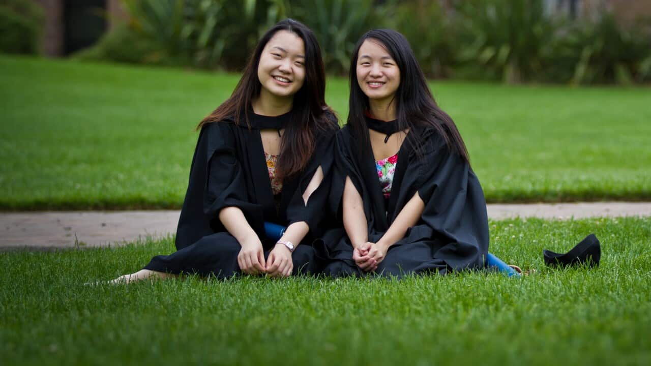 Two Chinese women pose for their graduation pictures just after the graduation ceremony at university in Canberra.