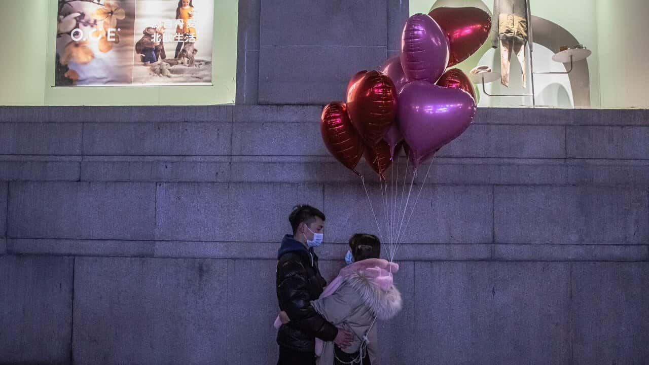 A couple wearing protective face masks pose for photos in Wuhan, China.