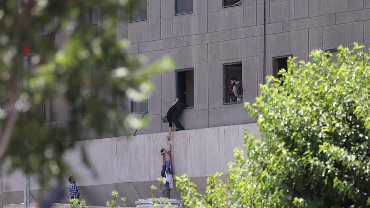 Iranian policemen try to help some civilians fleeing from the parliament building during an attack in Tehran, Iran