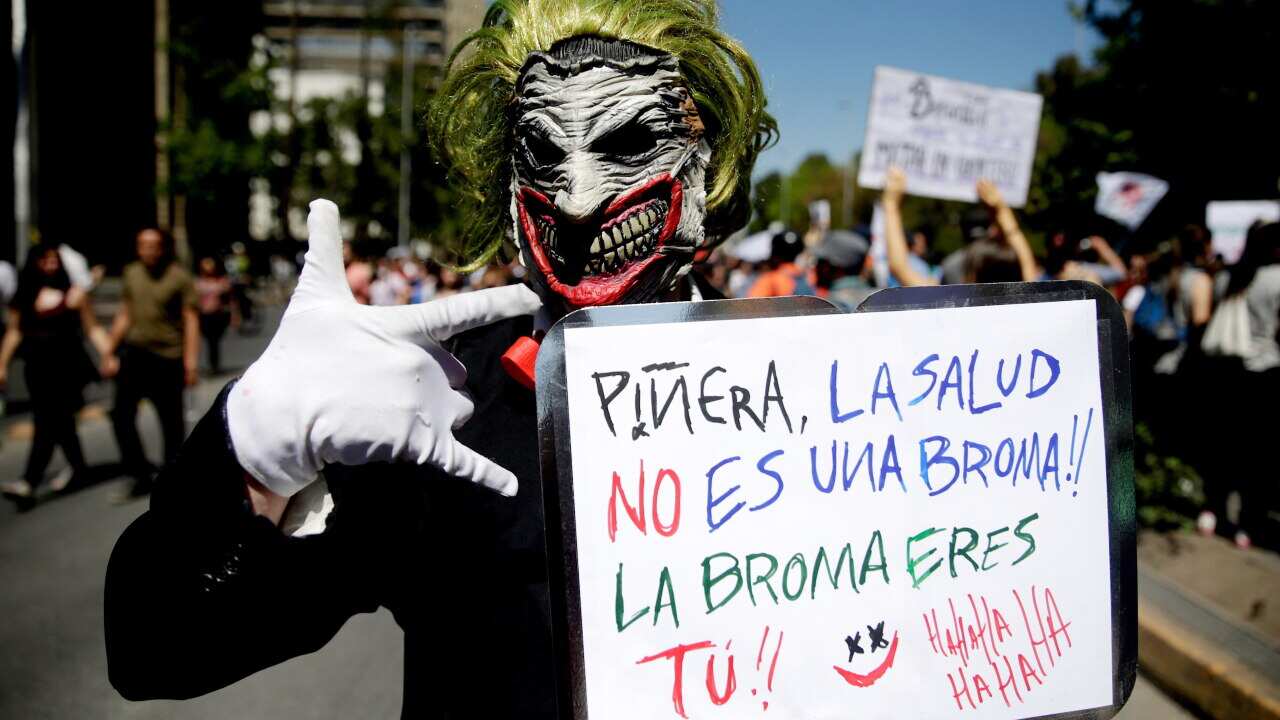 The protester's poster against President Sebastian Pinera reads 'Pinera, health is not a joke!! the joke is you!' on the sixth day of protests in Chile.