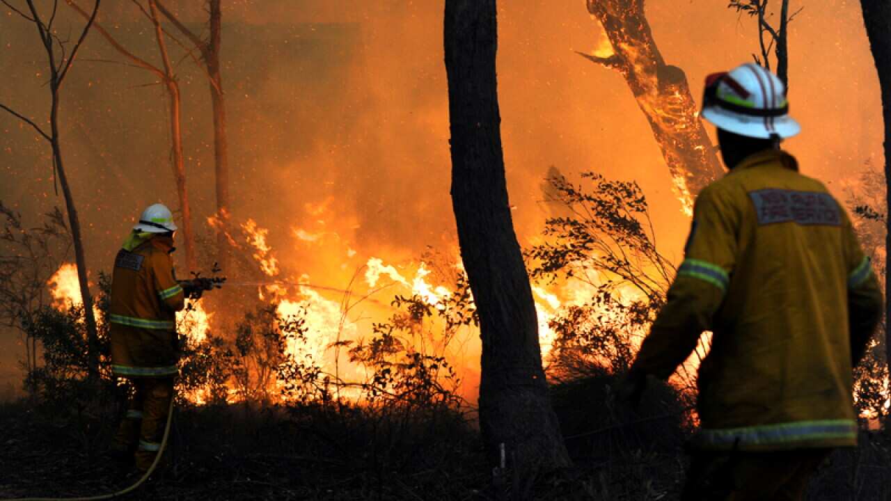 RFS volunteers try to save a house from a bushfire north of Lithgow