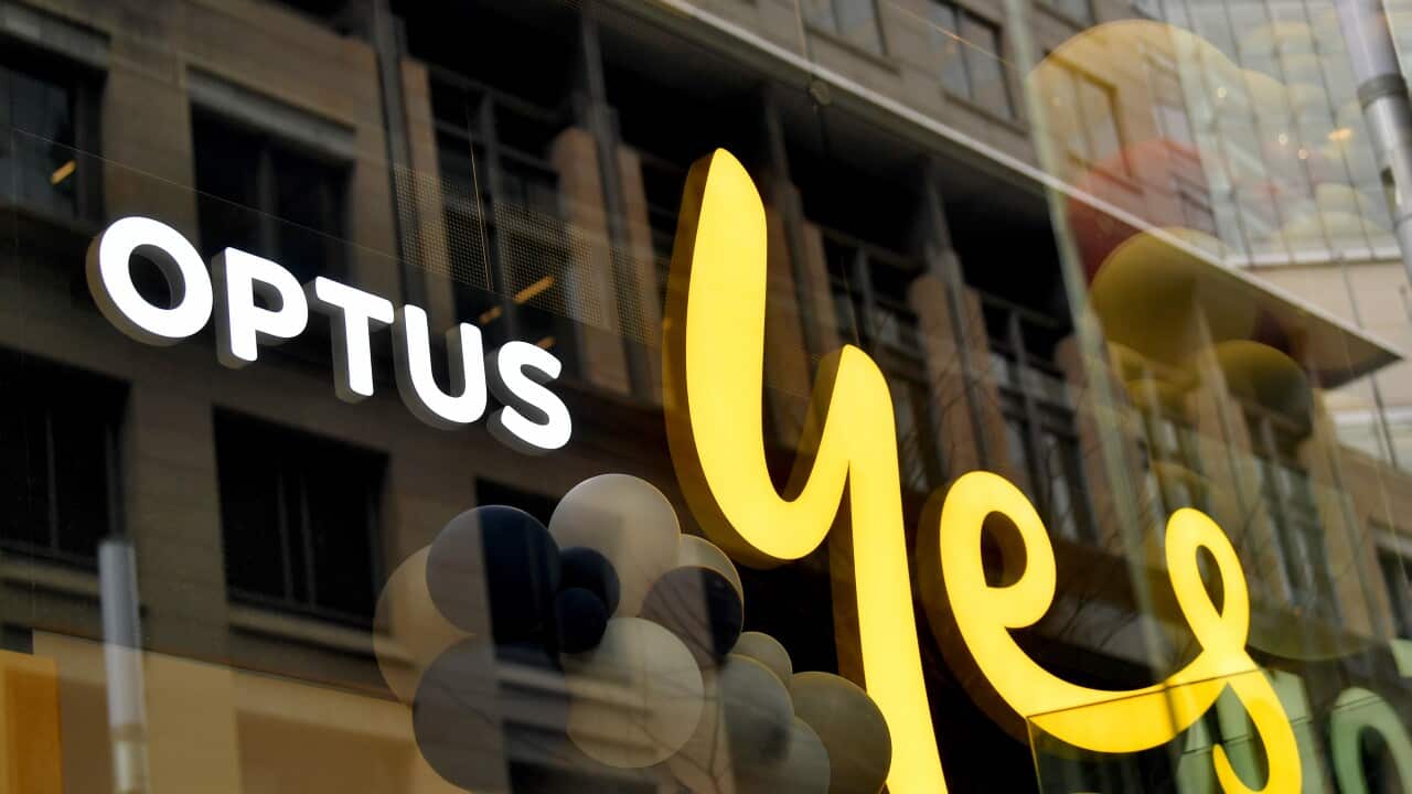 A close-up of a shop window with an illuminated sign with the words 'Optus yes'