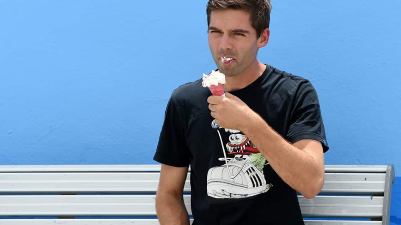 A man eats an ice-cream on a bench next to Bondi Beach in Sydney