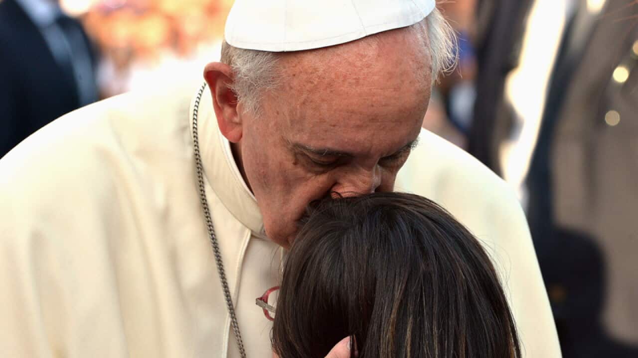 Pope Francis embraces a girl in Largo Carlo Felice in Cagliari