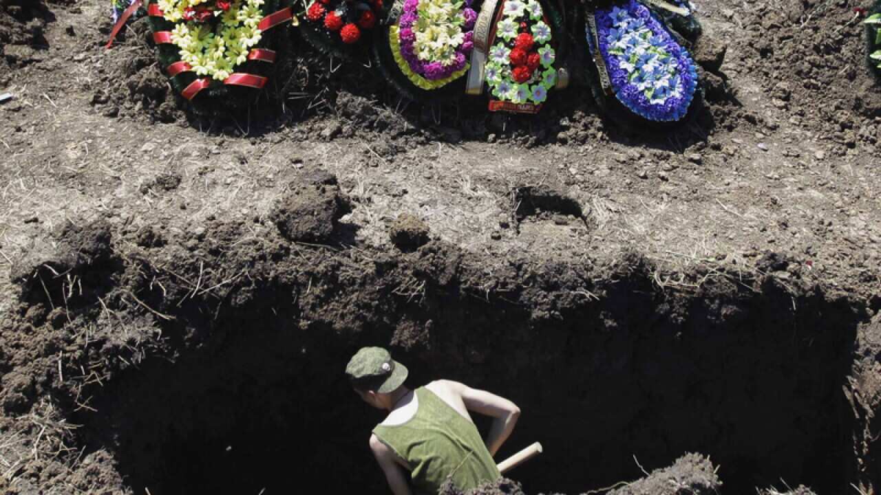 A soldier digs a grave for those who died during floods in Krymsk