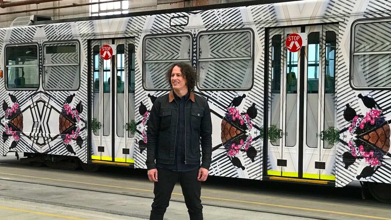Kent Morris next to a tram featuring his artwork
