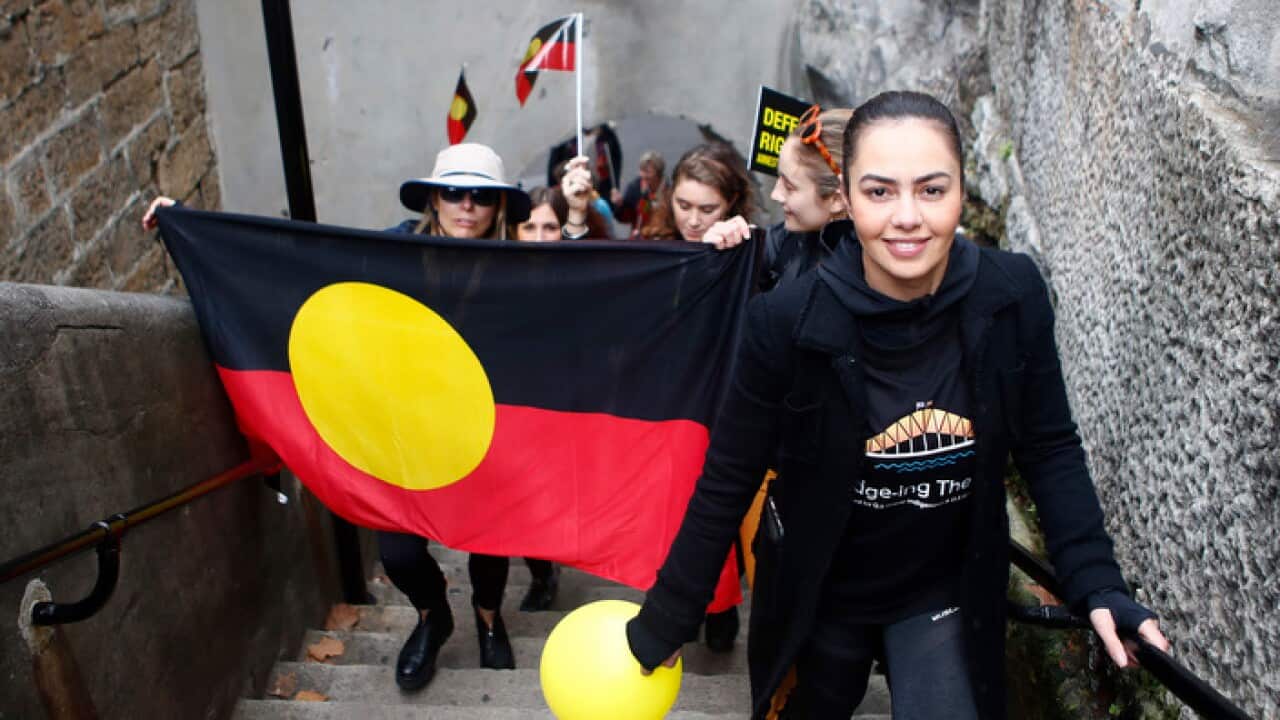 Cheree Toka and fellow demonstrators carry an Australian Aboriginal Flag up the steps of the Sydney Harbour Bridge. 