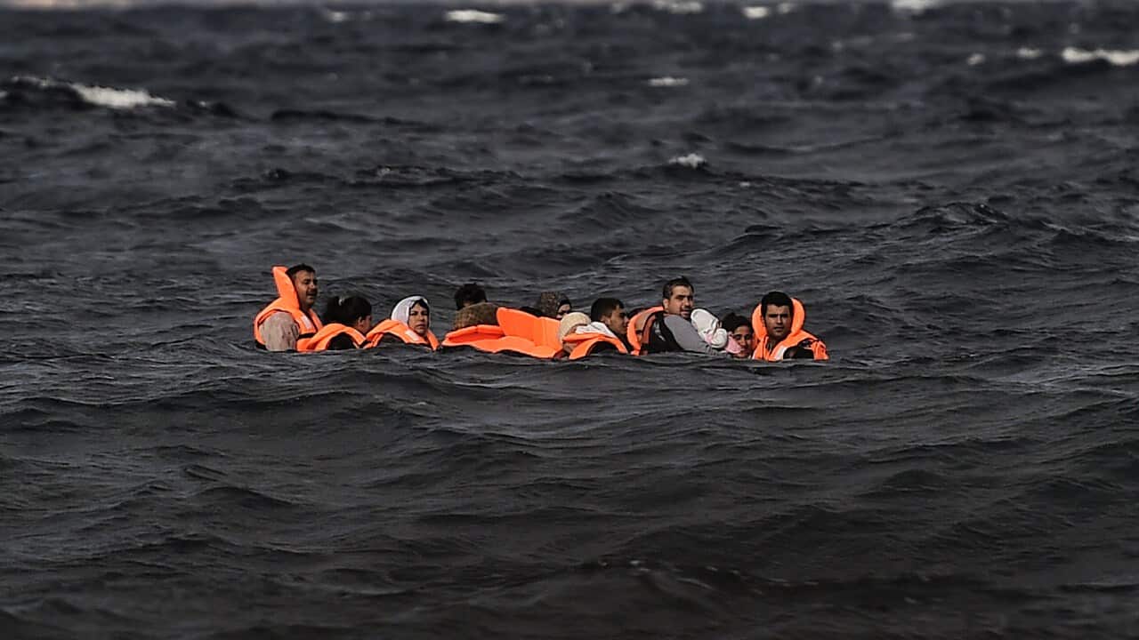 A group of migrants in a small boat at sea.