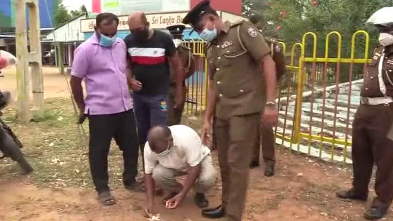 Selvaraja Gajendran lights a memorial lamp whilst the police are watching