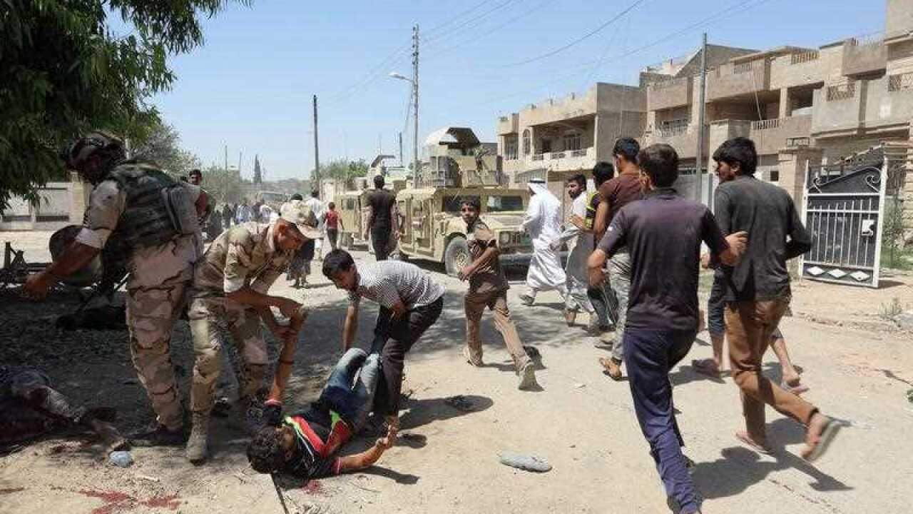 Iraqi people flee the scene as Iraqi soldiers evacuate dead bodies and wounded civilians.