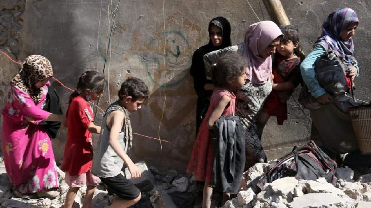 People walk among the ruins of Mosul