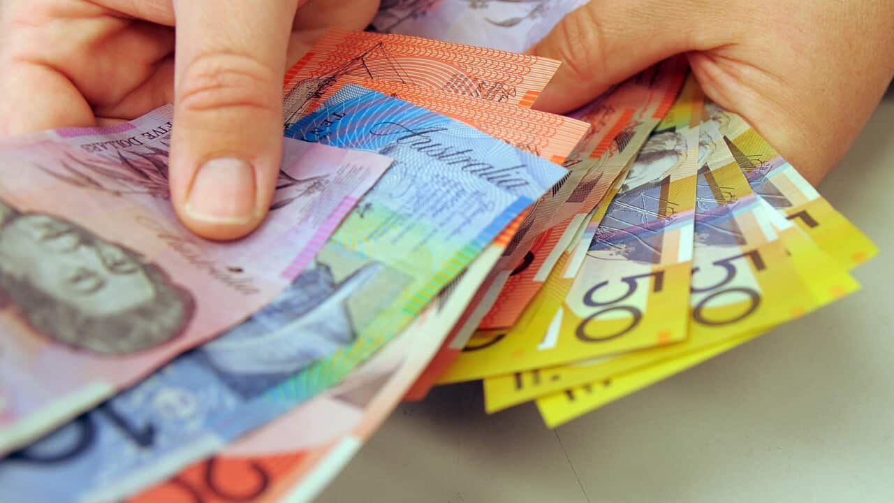 Two hands with various Australian currency notes.