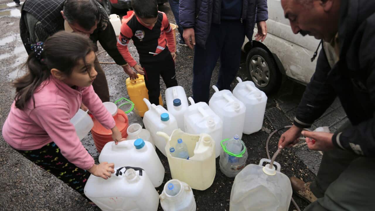 People fill plastic containers with water from a tap in Damascus