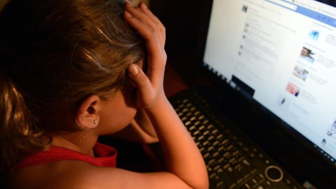 An upset young girl in front of a personal computer
