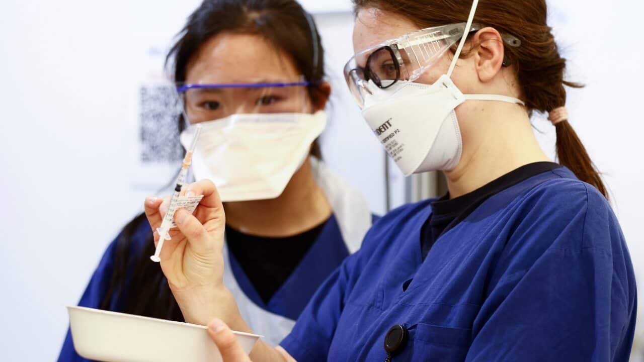 Health workers inspect a Pfizer vaccination syringe before administering the shot to a patient at a mass coronavirus vaccination hub at the Showgrounds in Melbourne, Monday, July 19, 2021. (AAP Image/Daniel Pockett) NO ARCHIVING