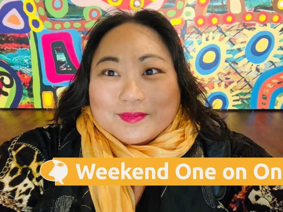 Dr Elaine Laforteza wearing a yellow scarf against a colourful mural.