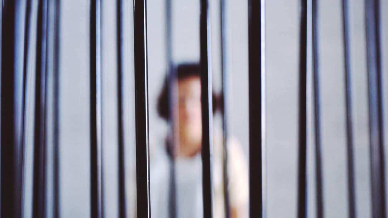A blurry photo of a woman in a jail cell.
