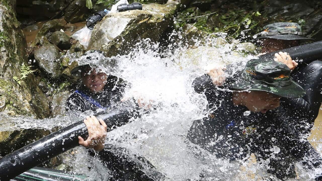 Thai soldiers try to connect a water pipe to pump out water from the flooded cave.