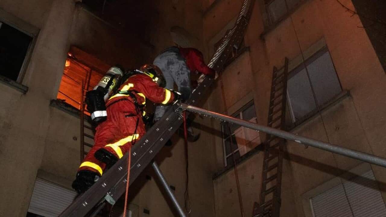 A firefighter helps residents escape the burning building
