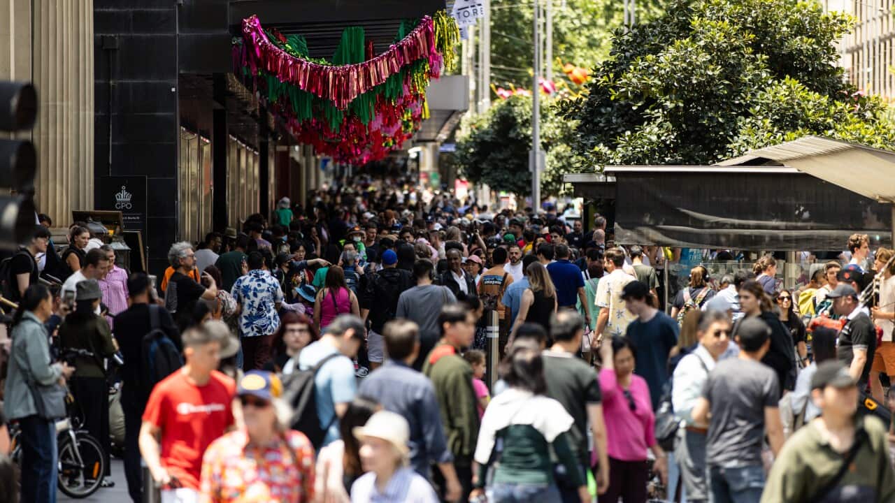 A large group of shoppers walk through a busy mall.