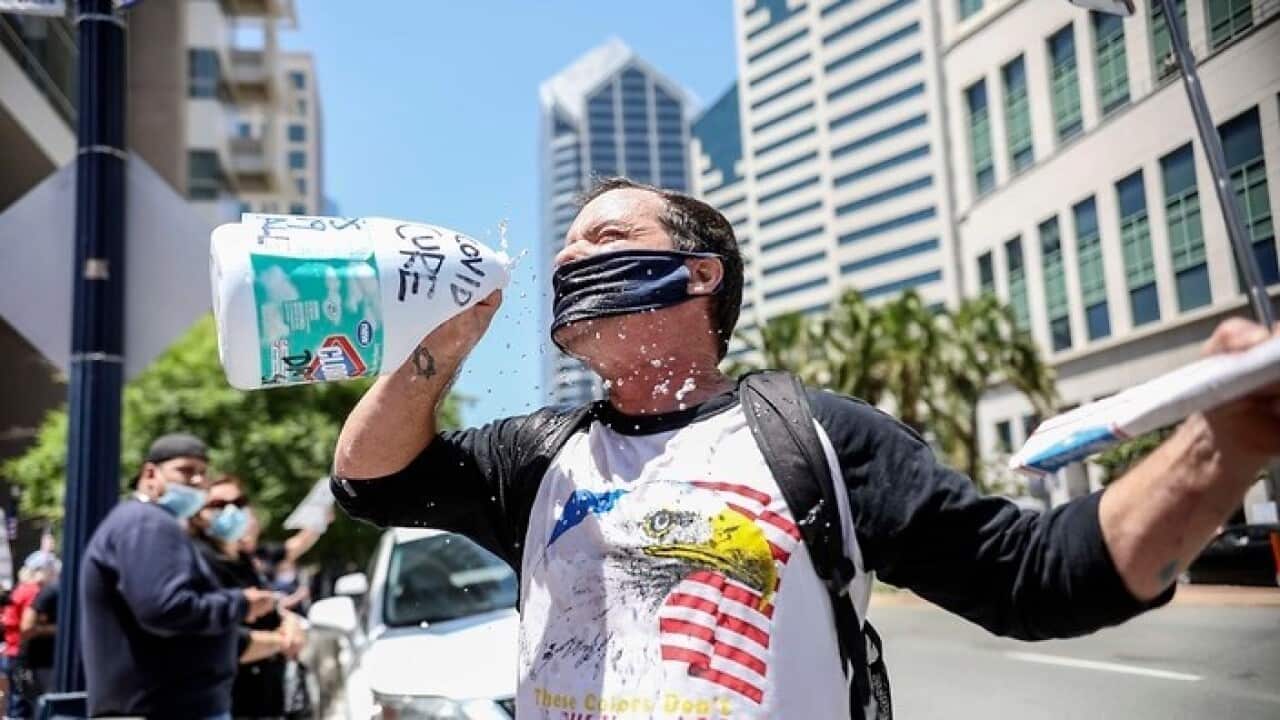 A demonstrator pretends to drink from a bottle of bleach during a rally in San Diego to re-open California.